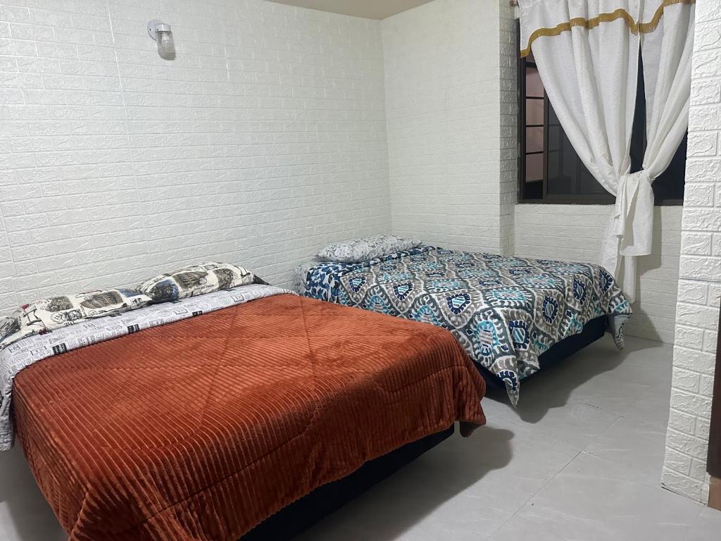 a bedroom with two beds and a window at Departamento con parqueadero céntrico in Baños