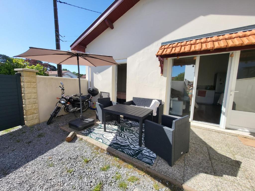 a patio with a table and an umbrella and a motorcycle at Maison Tarnos in Tarnos