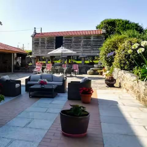 a patio with couches and chairs and an umbrella at La Casa del Río in Porto do Son