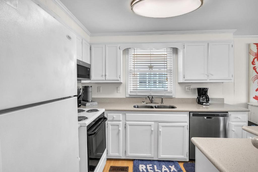 a kitchen with white cabinets and a white refrigerator at Sunkissed 2 by Oak Island Accommodations in Oak Island