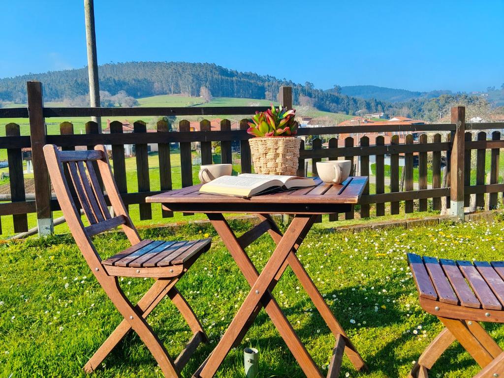 a picnic table with a book and two chairs at MINI PICONEIRO II in Pravia