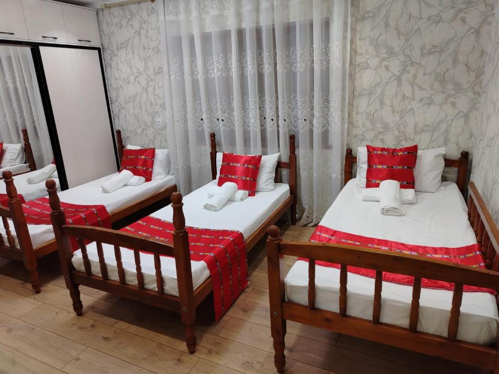 three beds in a room with red and white pillows at Sayora Guest House in Khorugh