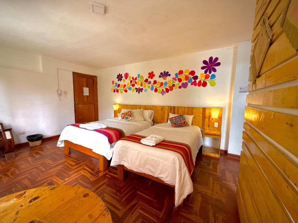 a bedroom with two beds with flowers on the wall at Sosa Andina House in Huaraz