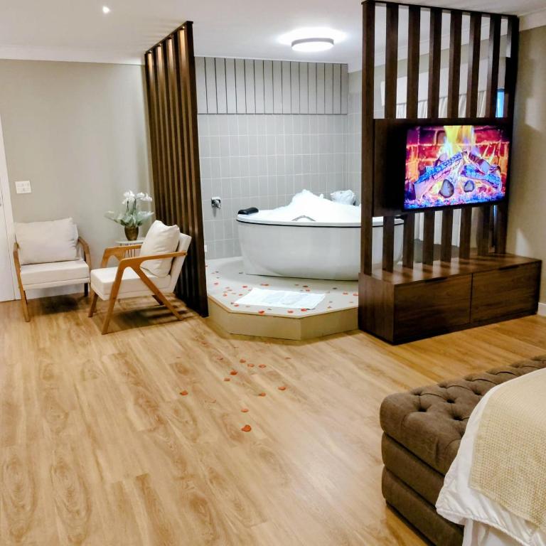 a bathroom with a tub and a tv in a room at Pousada Itália Moderna in Campos do Jordão