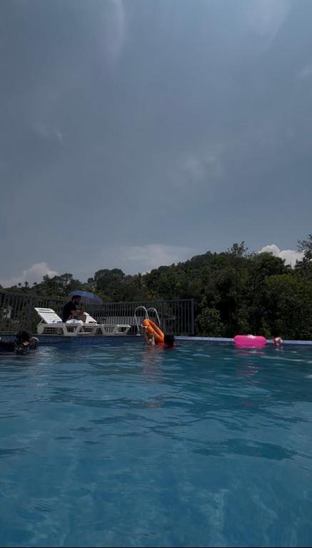 a swimming pool with people in the water at AJ Wayanad Suites in Kalpetta