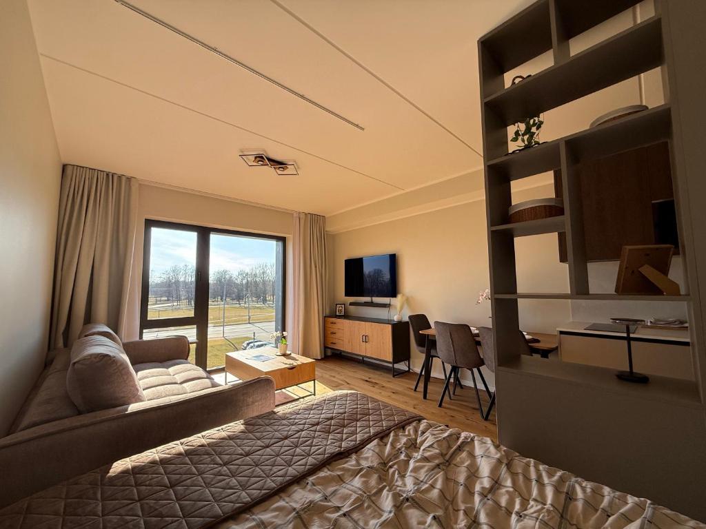 a living room with a bed and a desk and a television at Nameja Apartamenti in Riga
