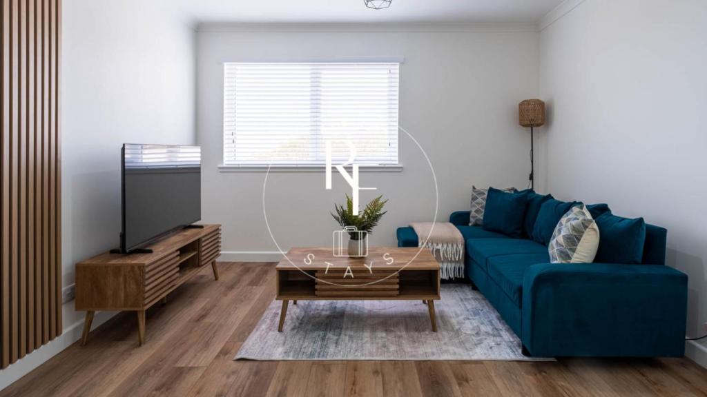 a living room with a blue couch and a tv at The Den at Abernethy in Peterhead