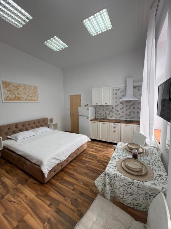 a white bedroom with a bed and a table at November Central Studio in Lugoj