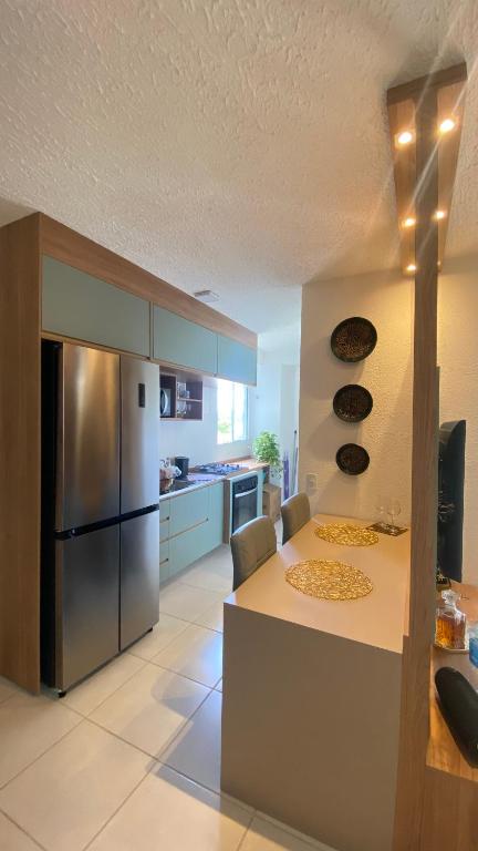 a kitchen with a table and a stainless steel refrigerator at Aconchego Perto das praias da região oceânica in Niterói