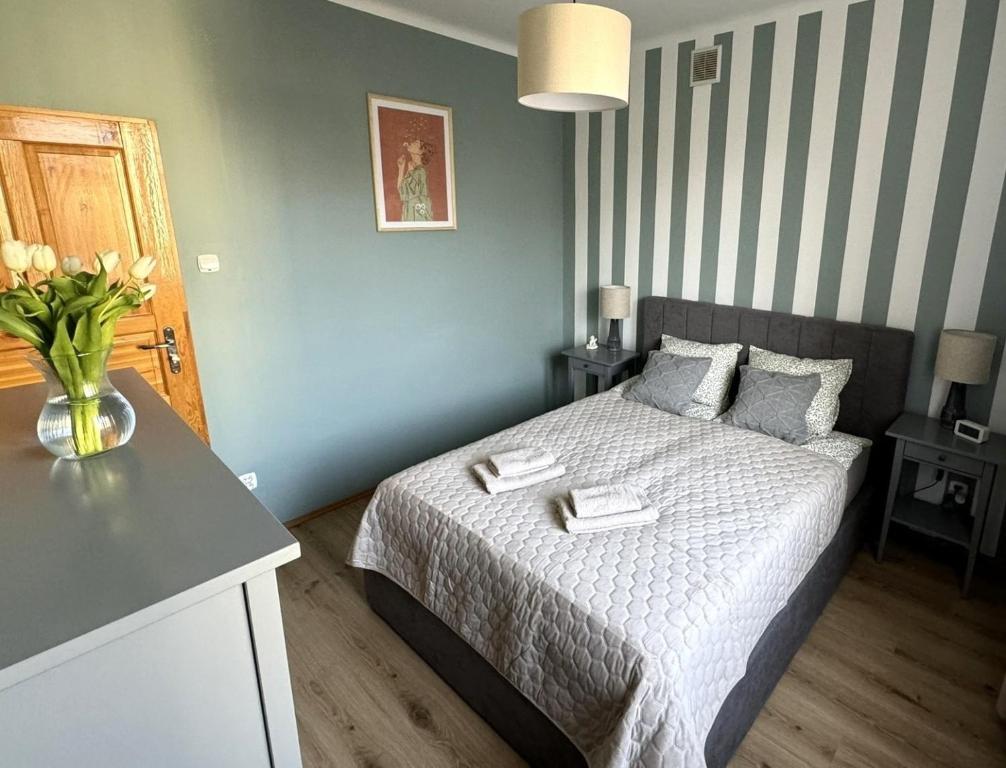 a bedroom with a bed with a vase of flowers on it at Akacja Centrum Apartament in Rzeszów
