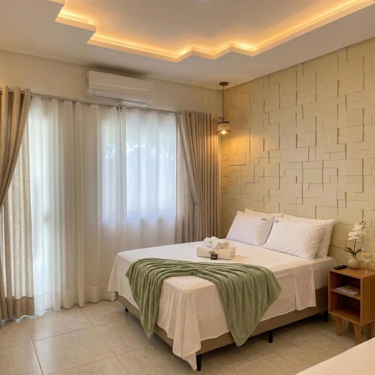 a bedroom with a large white bed with a window at Village Park Hotel in Pires Ferreira