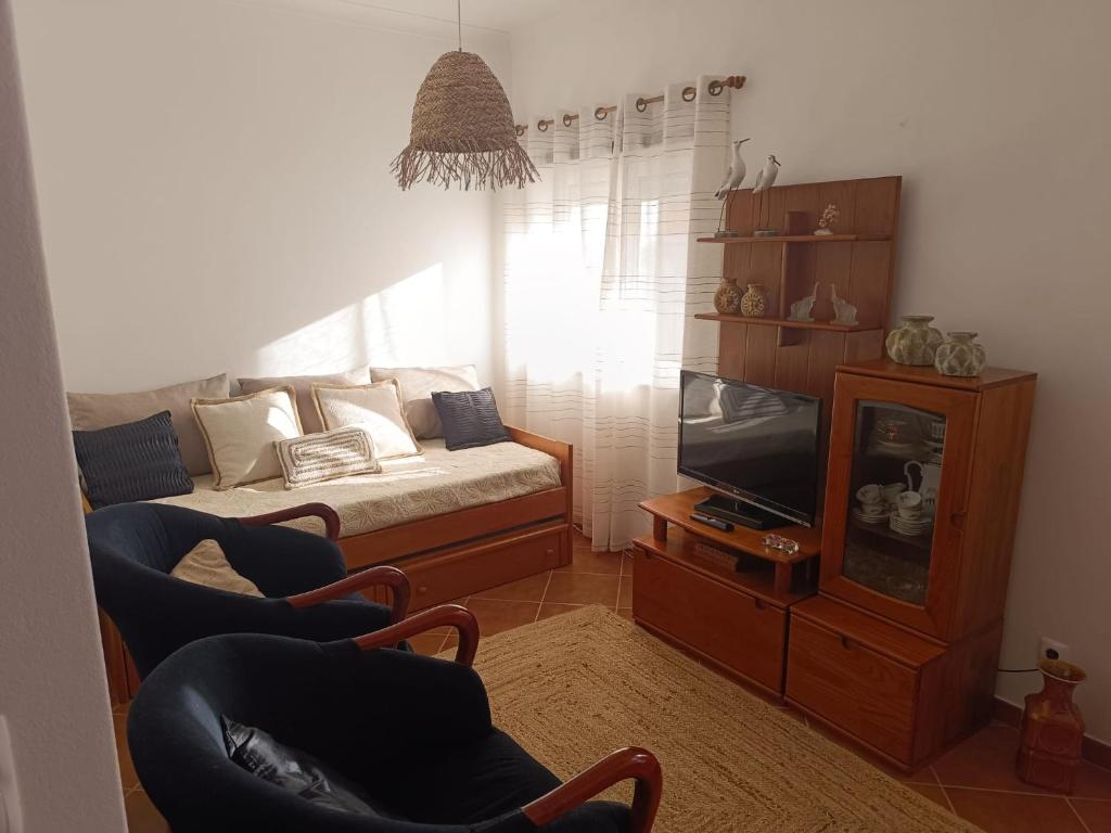 a living room with a couch and a tv at Cantinho da Xica in Lagos