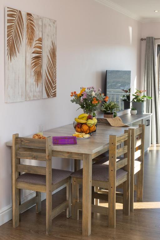 a wooden table and chairs with a bowl of fruit on it at Stunning Ocean & Mountain View Apartment in Glencairn