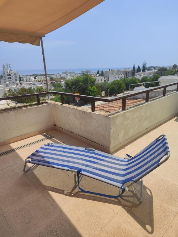 a lounge chair on a balcony with an umbrella at Profelia Sea View Apartment in Paralimni