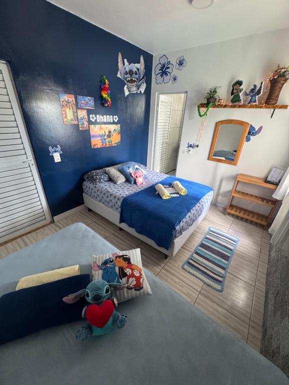 a small bedroom with a bed and a blue wall at Suite Lilo e Stitch - Pousada Castelo do Luar in Penha