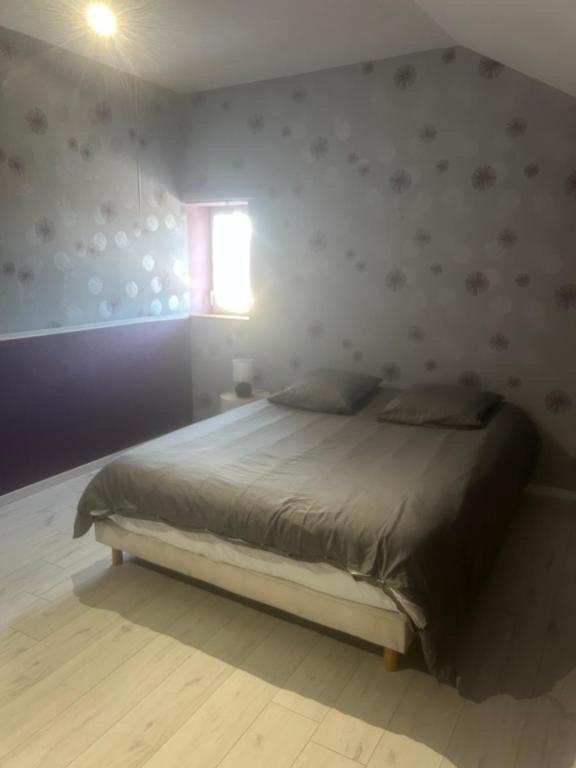 a bedroom with a bed in a room with a window at Au Petit Bouchon in Le Breuil