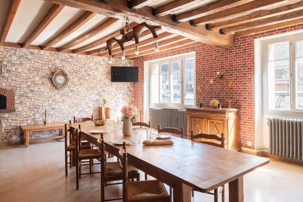 a dining room with a wooden table and a brick wall at Bienvenue chez Pépère in Nitry