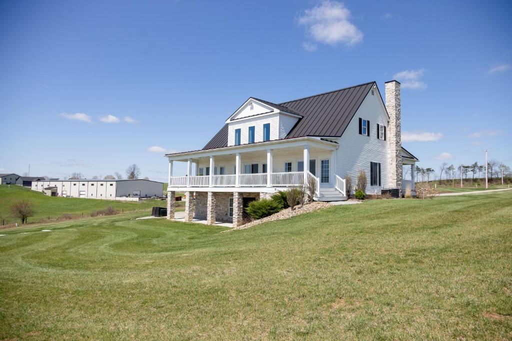 a white house on a hill with a green field at The Gathering Premier stay for Large Groups in Millersburg