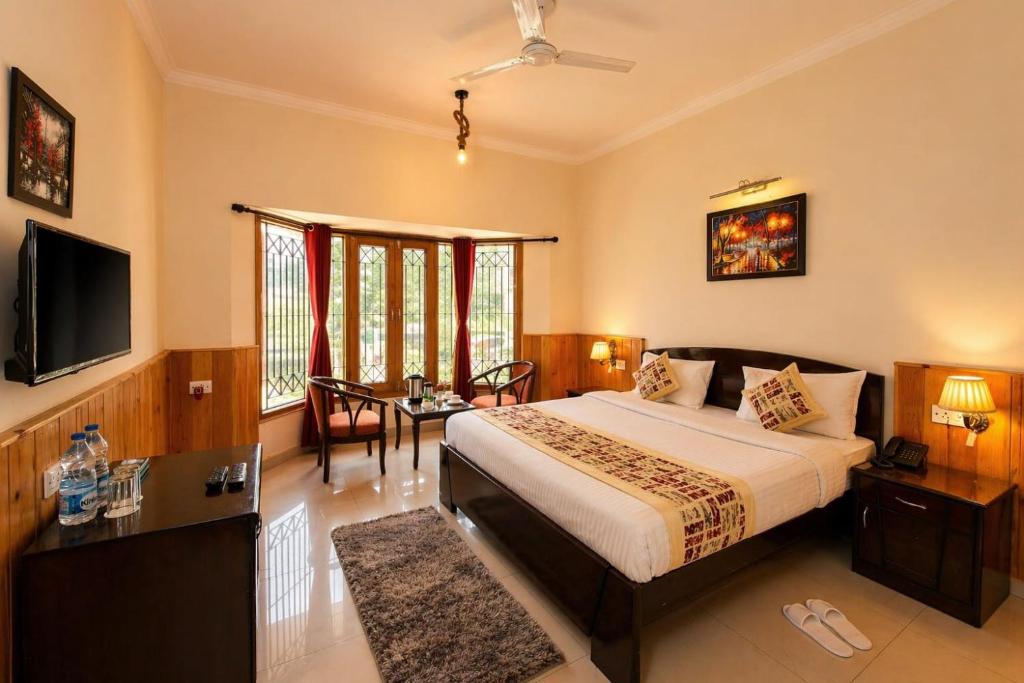 a bedroom with a bed and a television and a table at The Regal IVY Hotel in Nainital