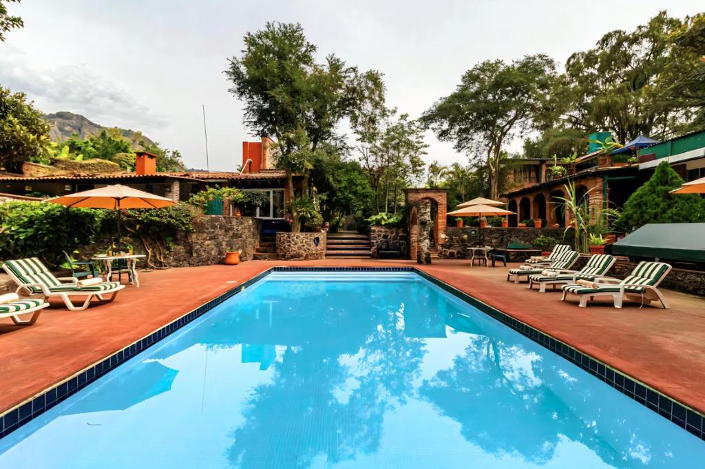 a pool at a house with chairs and umbrellas at Hotel La Posada del Valle in Tepoztlán