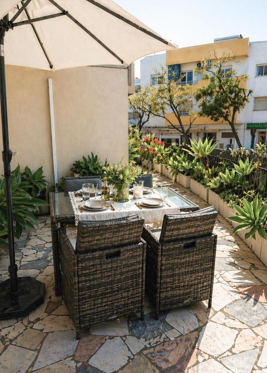 an outdoor table with wicker chairs and an umbrella at 3B flat in Portimão