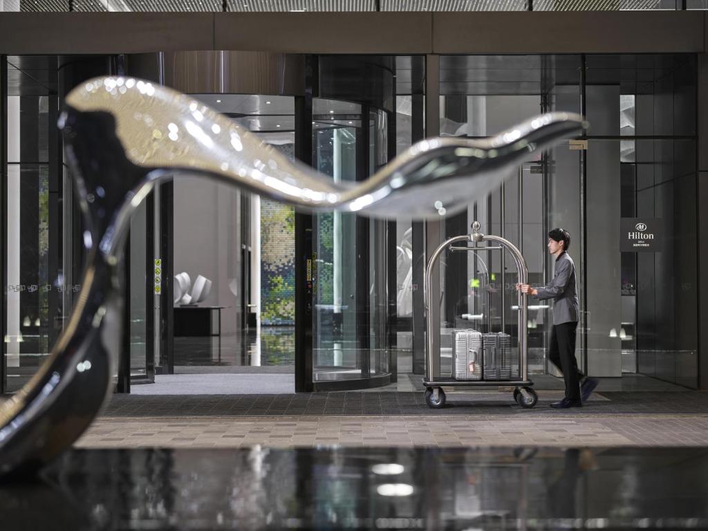 a man with a luggage cart in front of a building at Hilton Zhuji in Zhuji