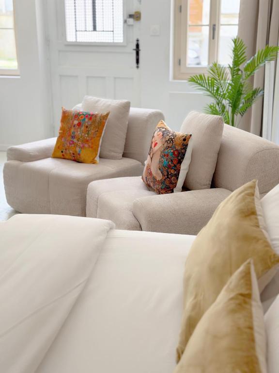 a white living room with two couches and pillows at Atelier Marguerite, plain-pied au cœur de Tonnerre in Tonnerre