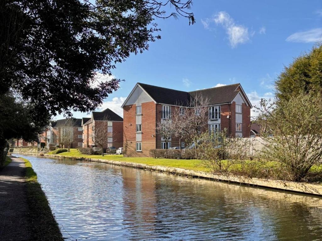 a building next to a river in front of a building at 2 Bedroom Apartment in Exhall