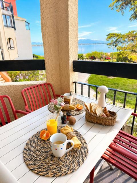 a table with breakfast foods and drinks on a balcony at Terrasse vue Etang, piscine Séjour détente in Le Barcarès