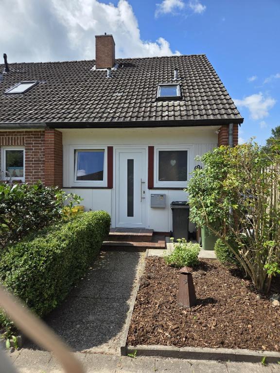 a small house with a white door and bushes at Lüdde Stuv am Meer in Husum
