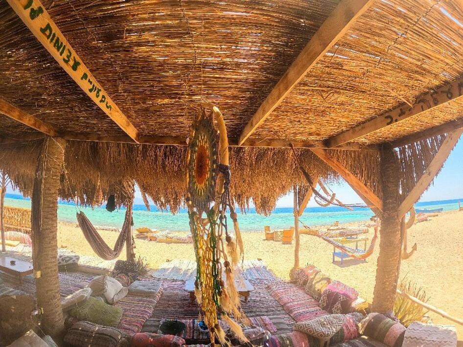 a beach with some chairs and a straw umbrella at Galuma magbul camp in Dahab