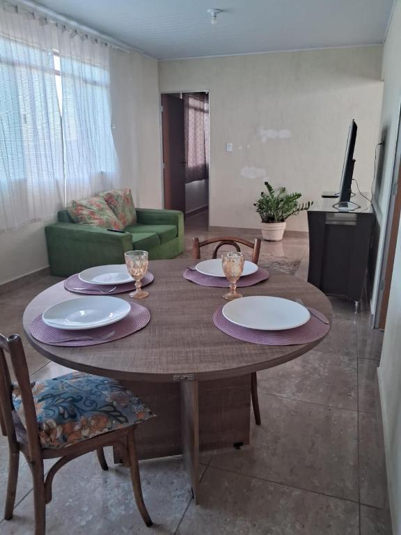 a living room with a wooden table with plates and chairs at Casa 2 quartos perto Centro Ipatinga e aeroporto in Santana do Paraíso