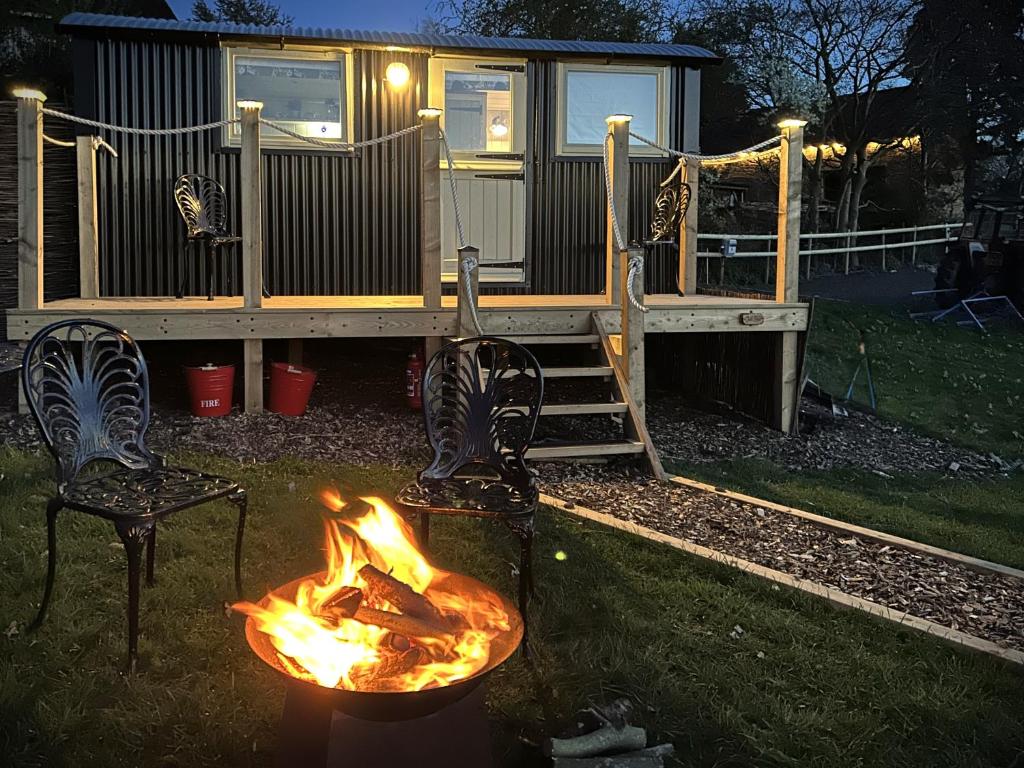 a fire pit with two chairs and a house at Spinney Wood Glamping, Oak Hut in Bewdley