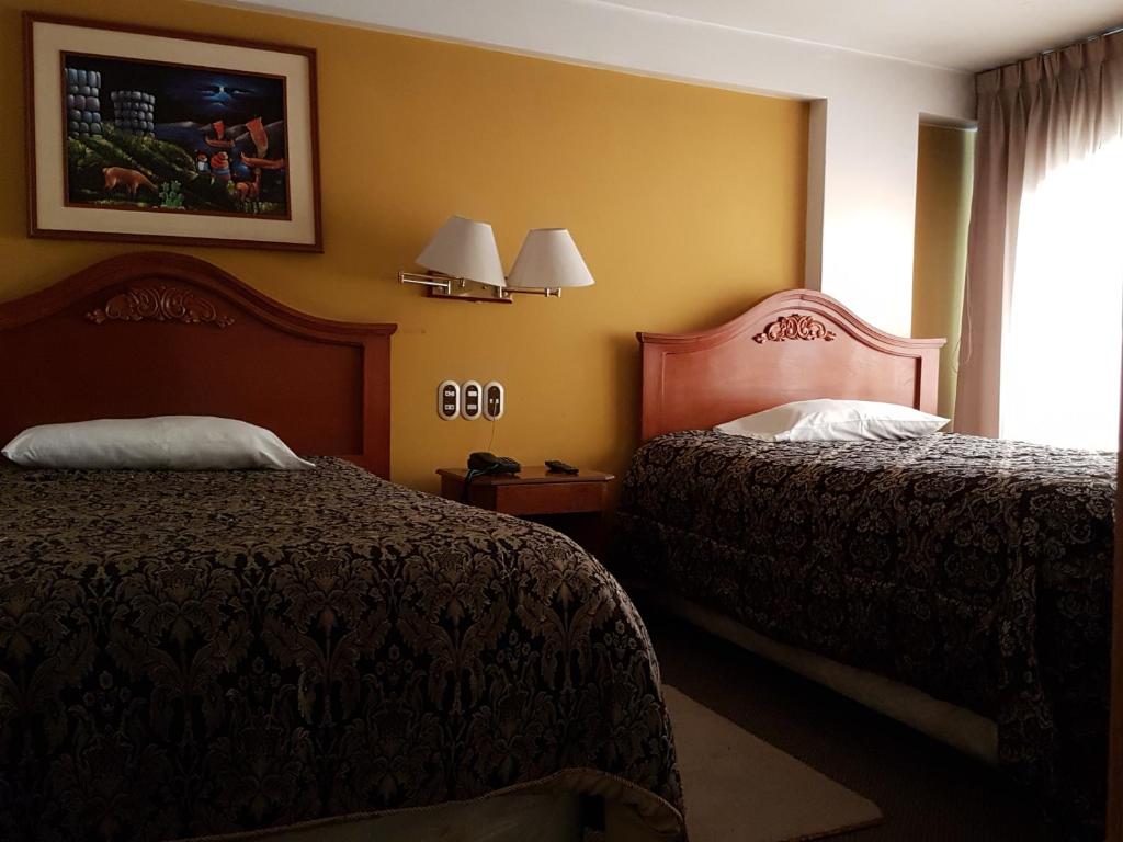 a hotel room with two beds and a window at Cordelius Hotel in Puno