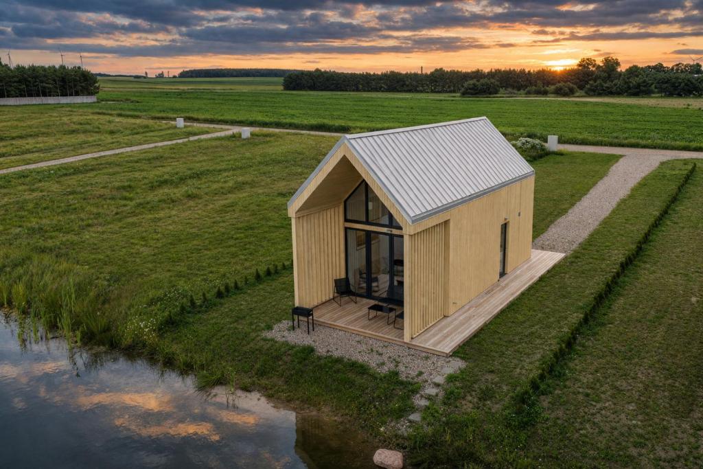 a small wooden house in a field next to a river at Palanga Waterhouse in Kiauleikiai
