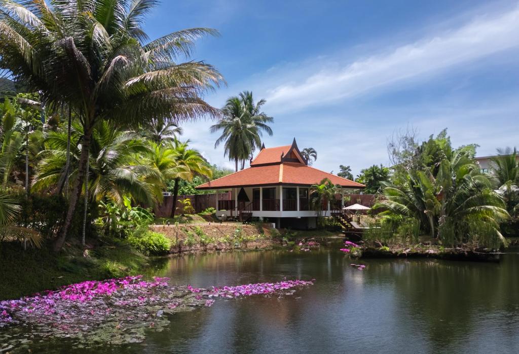 a house with purple flowers in the water at Sontaya - Lakeside Studio Villa in Ban Khao Thong