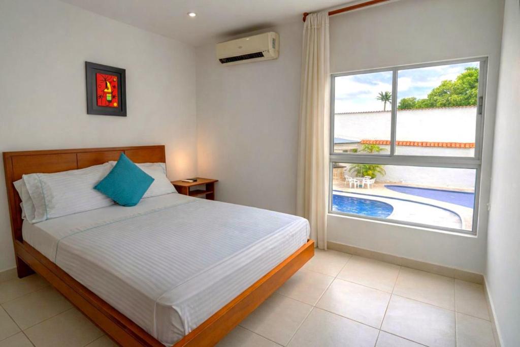 a bedroom with a bed and a window with a pool at Casa Serena Hotel Boutique in Melgar