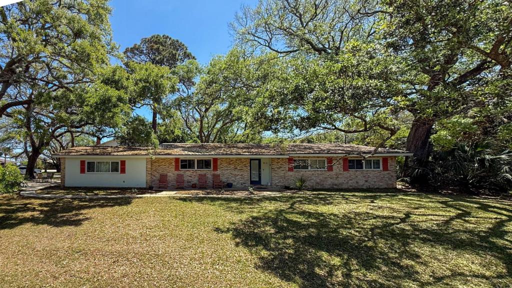 a small brick house in a yard with trees at Cuddlefish in Jekyll Island