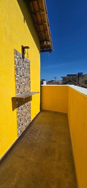 a yellow wall with a shelf on the side of a building at Pousada Sol Radiante in São Pedro da Aldeia
