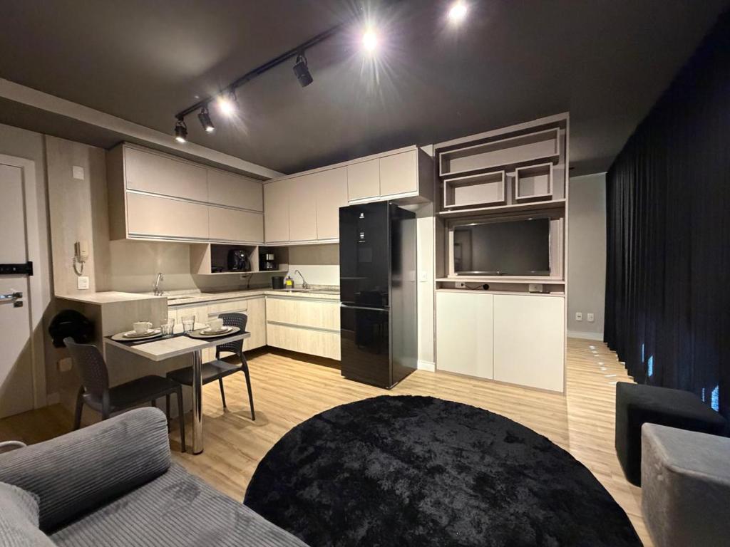 a living room with a black refrigerator and a kitchen at Studio aconchegante in Belo Horizonte