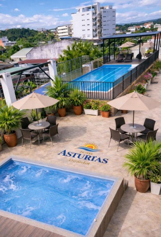 a pool on the roof of a building with tables and umbrellas at Hotel Asturias in Girardot