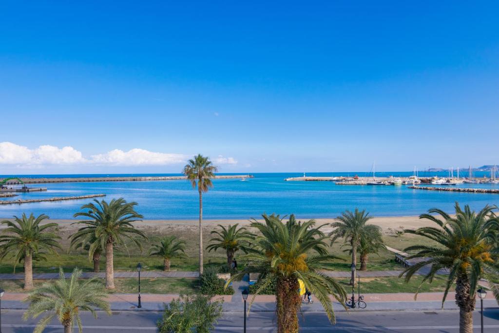 a view of a beach with palm trees and the ocean at George's Poet Maisonette in Rethymno Town