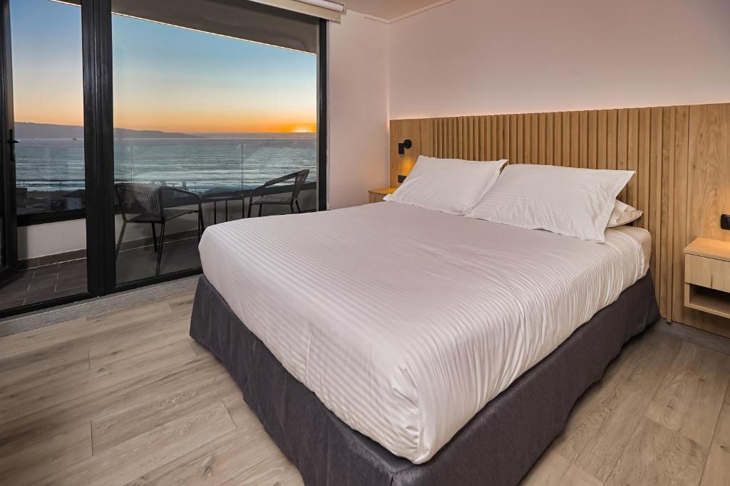a bedroom with a bed and a view of the ocean at Arka Hotel in Viña del Mar