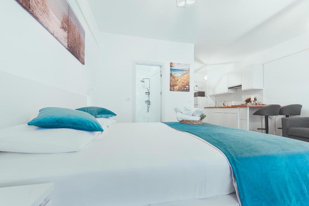a white bedroom with a large bed with blue pillows at TiLiA Breeze Studio Saturn in Saturn