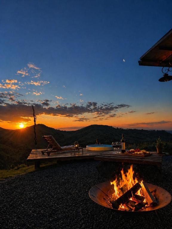 a fire pit on a patio with the sunset in the background at Cabana do Retiro Refúgio Rústico na Natureza! in Alto da Conceição
