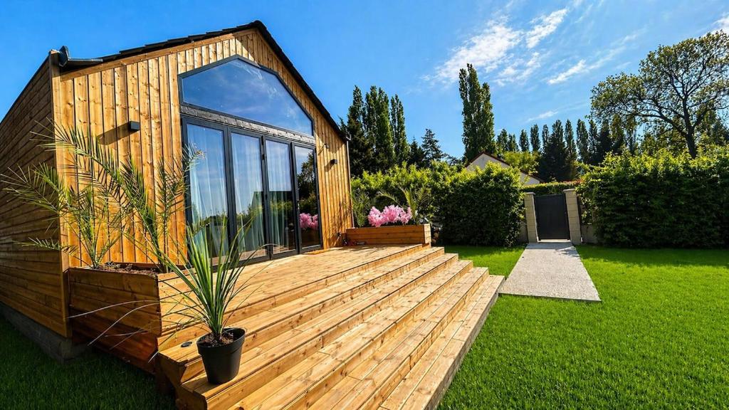 a small wooden deck with a house in a yard at Cottage de luxe en bois in Longnes