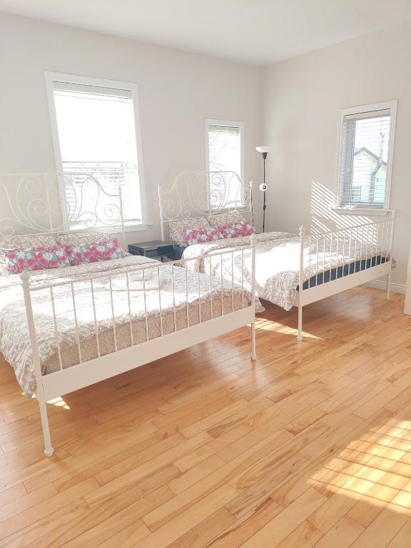 two beds in a room with a wooden floor at Sunny Ensuite Room with 2 Queen Beds-2A in Halifax