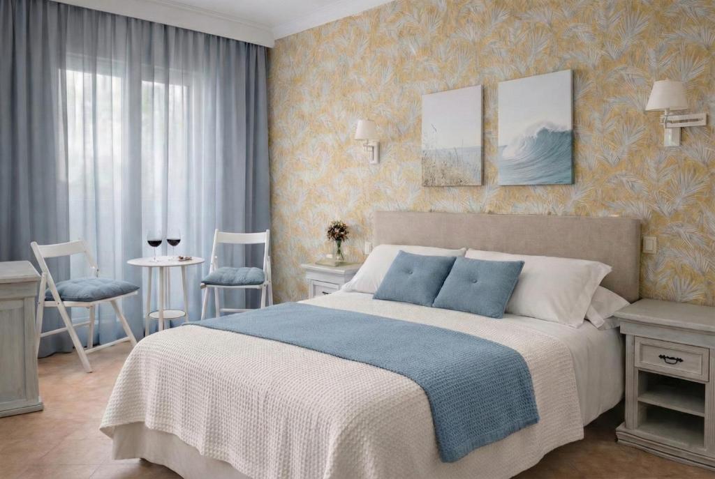 a bedroom with a bed and two chairs and a table at Hotel Playa del Carmen in Barbate