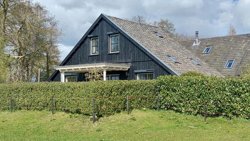 a black house with a fence in front of it at Ruime Vakantiewoning - Hoeve Niets meer - met eigen privé terras en tuin in Balkbrug
