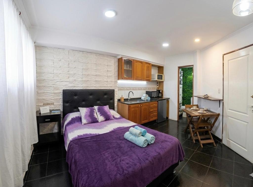 a bedroom with a purple bed and a kitchen at CHE LOLITA HOUSE in Buenos Aires